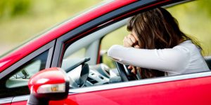 Young woman sitting depressed in car after car accident